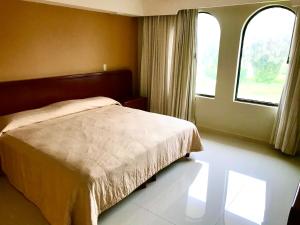 a bedroom with a bed and two windows at Hotel Villas Dali Veracruz in Veracruz