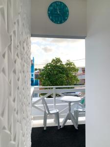 a clock on a wall above a balcony with a table and chairs at Suítes Vovó Zilda in Maragogi