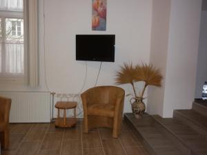 a living room with a chair and a tv on the wall at Szép-Lak Makó in Makó