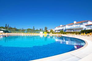 a large swimming pool with chairs and a building at Apartment Oásis Park in Portimão