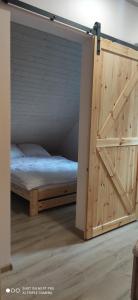 Ce lit se trouve dans un dortoir doté d'une porte en bois. dans l'établissement EkoGaik, à Lewin Kłodzki