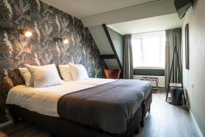- une chambre avec un grand lit et du papier peint floral dans l'établissement Hotel het Anker van Texel, à De Cocksdorp