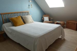 1 dormitorio con 1 cama blanca grande con almohadas amarillas en Locmariaquer - Duplex 4 pers - accès direct à la plage, en Locmariaquer