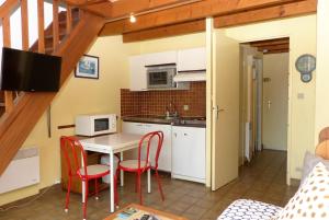 cocina con mesa, sillas y microondas en Locmariaquer - Duplex 4 pers - accès direct à la plage, en Locmariaquer