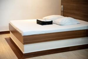 a bed with a white mattress and a black suitcase on it at Prime Motel Campinas in Campinas