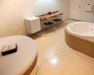 ein Badezimmer mit einer Badewanne, einem Tisch und einem Waschbecken in der Unterkunft Prime Motel Campinas in Campinas