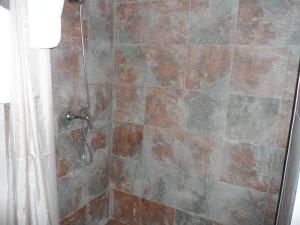 y baño con ducha y pared de azulejos. en Hostal Via Del Caminante, en Madrigalejo