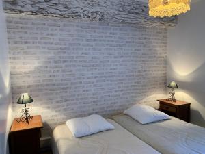 2 bedden in een slaapkamer met een bakstenen muur bij Gites de la Thiau in Briare