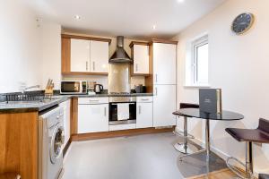 a kitchen with white cabinets and a stove top oven at Royal Sovereign with Parking - TV in every Bedroom! in Swansea