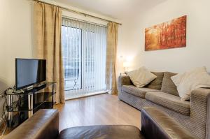 a living room with a couch and a tv at Royal Sovereign with Parking - TV in every Bedroom! in Swansea