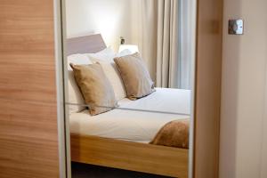 a mirror reflection of a bed in a bedroom at Royal Sovereign with Parking - TV in every Bedroom! in Swansea