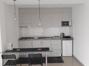 a kitchen with white cabinets and a table with chairs at Apto T1 Sweet Home in Praia