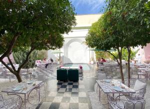 an outdoor patio with tables and chairs and trees at Appartement de prestige climatisé à l'hivernage 400m de la Gare in Marrakech