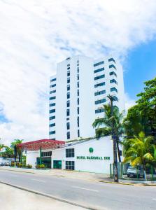 Hotel Nacional Inn Recife Aeroporto في ريسيفي: مبنى ابيض امامه نخله