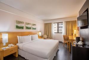 Una habitación de hotel con una cama grande y un televisor. en Meliá Campinas, en Campinas