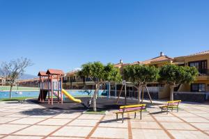 a playground with a slide and benches in a courtyard at Holiday House Atlantico in Costa Del Silencio