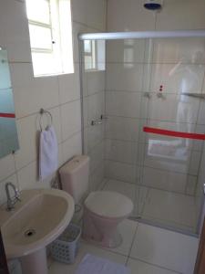 a white bathroom with a toilet and a sink at Pousada Sol de Minas in Monte Sião