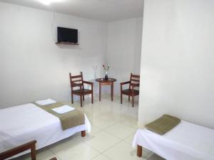 a room with two beds and a table and chairs at Pousada Sol de Minas in Monte Sião