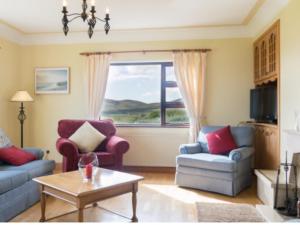 a living room with two chairs and a table and a window at Beachmount House in Ventry