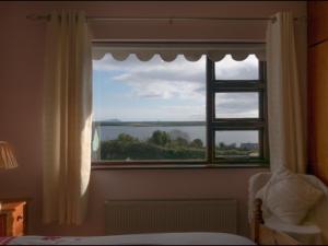 a window in a bedroom with a view of the ocean at Beachmount House in Ventry