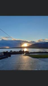 a sunset over a parking lot with the sun setting at Beachmount House in Ventry