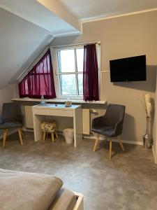 1 Schlafzimmer mit einem Schreibtisch, 2 Stühlen und einem TV in der Unterkunft Hotel Kellermann in Overath