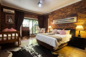 a bedroom with a bed and a brick wall at Doringpoort Lodge in Marloth Park