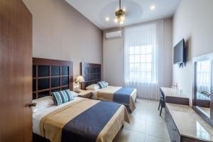 a hotel room with two beds and a television at Tecnohotel Casa Villamar in Progreso