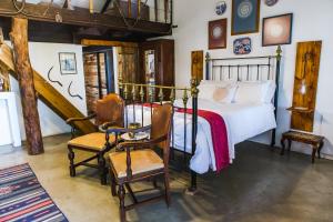 a bedroom with a bed and two chairs at Schaftplaas Cottages in Langebaanweg
