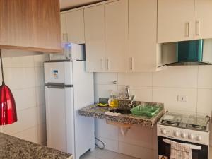 uma cozinha com armários brancos e um frigorífico branco em Morro Vermelho em Goiânia