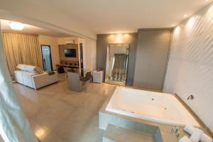 a large bathroom with a tub and a living room at Hotel Eldorado in Paracatu