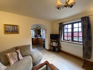 a living room with a couch and a window at Thompsons Arms Cottages in Flaxton