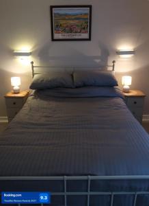a bedroom with a bed with two lights on two tables at Boutique cottage in the heart of Winchcombe in Winchcombe