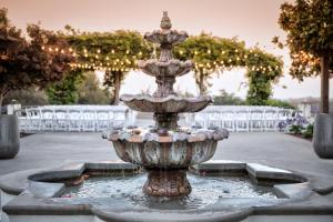 a fountain in a courtyard with white chairs at Chaminade Resort & Spa in Santa Cruz