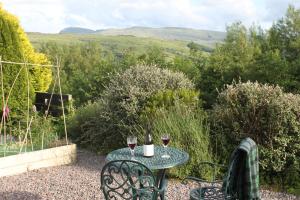 a table with two glasses of wine on a patio at Heatherbank Guest House in Strontian