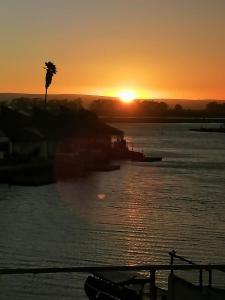 un coucher de soleil sur une étendue d'eau avec un arbre dans l'établissement la foi, à Velddrif