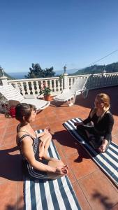two women sitting on mats on a patio at Casa La Bodega in Hermigua