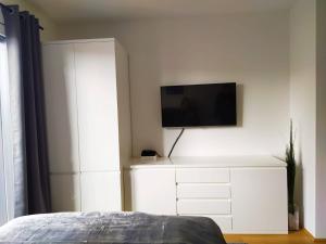 um quarto com uma cómoda branca e uma televisão na parede em Cosy Park Apartment City Center em Viena