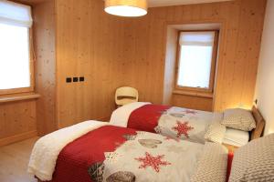 a bedroom with two beds and a couch and two windows at CASA TANTI in Bormio