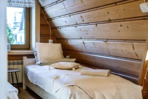 Cama en habitación con pared de madera en Willa w Ubocy - "Jacuzzi i Sauna w ofercie dodatkowo płatnej", en Murzasichle