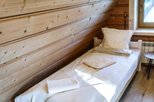 Cama en habitación con pared de madera en Willa w Ubocy - "Jacuzzi i Sauna w ofercie dodatkowo płatnej", en Murzasichle