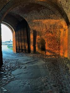 um velho túnel com uma parede de tijolos e um arco em Fästningens em Varberg