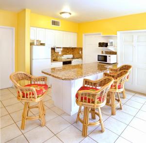 uma cozinha com paredes amarelas e um balcão com cadeiras em Tropic Seas Resort em Fort Lauderdale