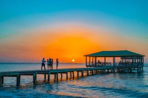 people standing on a pier at the beach at sunset at La Ensenada Beach Resort in Tela