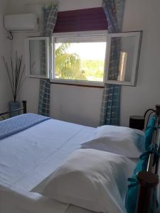 1 dormitorio con cama blanca y ventana en Loca Vacances, en Sainte-Anne