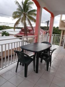 a black table and chairs on a porch with a palm tree at Loca Vacances in Sainte-Anne