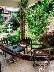 a hammock with chairs and a table in a garden at Chez Max Pousada in Morro de São Paulo