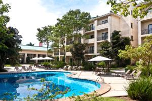 a hotel with a pool and chairs and umbrellas at Hotel Panamby Guarulhos in Guarulhos
