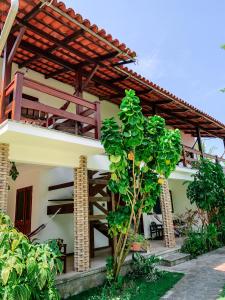 a house with a wooden roof and a tree at Chez Max Pousada in Morro de São Paulo
