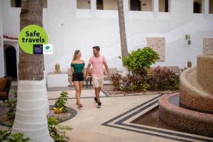 a man and a woman walking through a courtyard at GR Caribe Deluxe By Solaris All Inclusive in Cancún